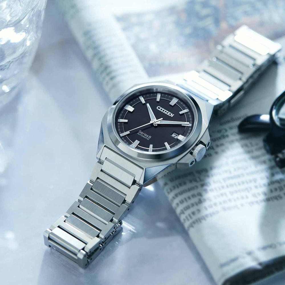 Montre Citizen Series 8 sur journal, cadran noir, bracelet argenté, gros plan