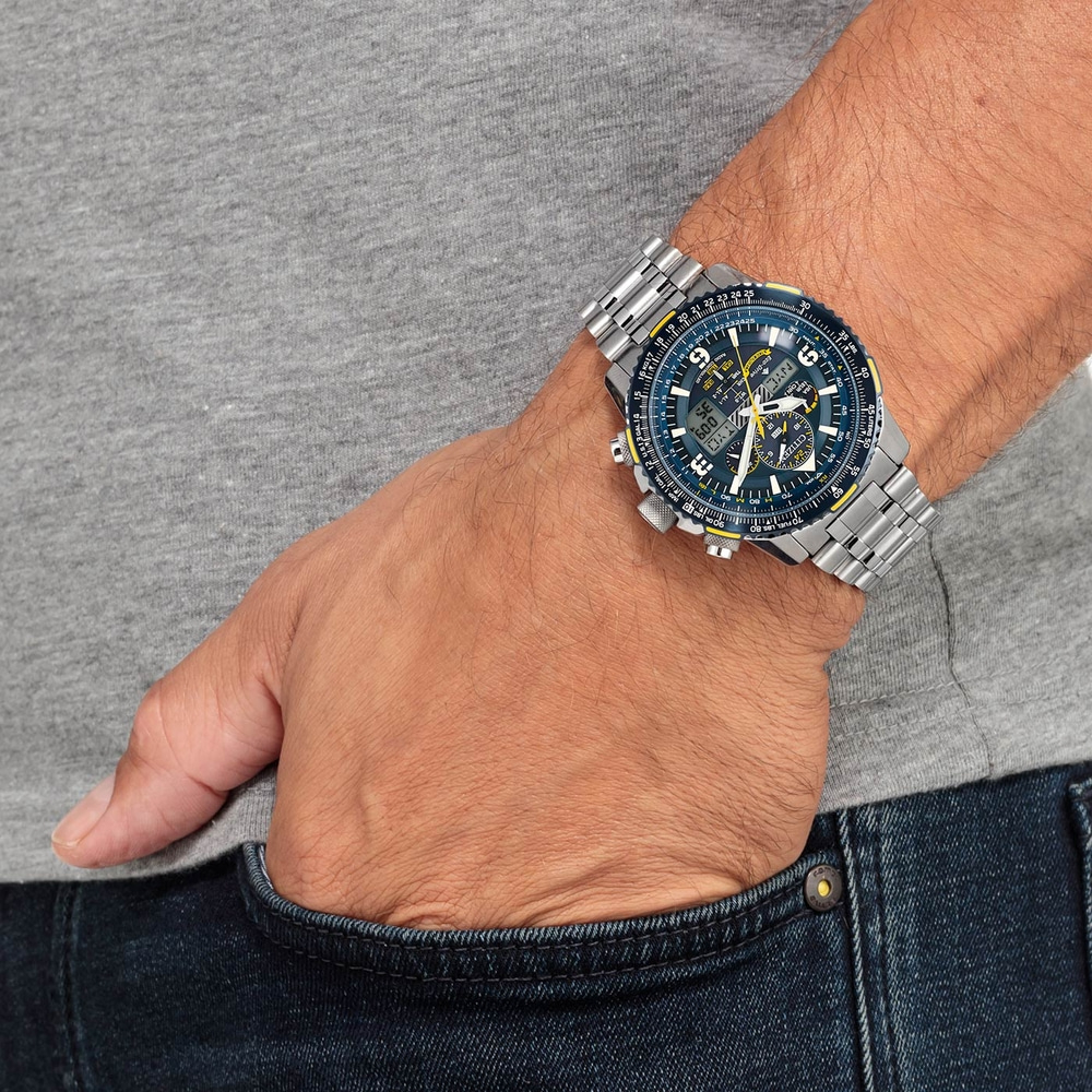 Homme portant une montre Citizen, main dans la poche, chemise grise, jean bleu.