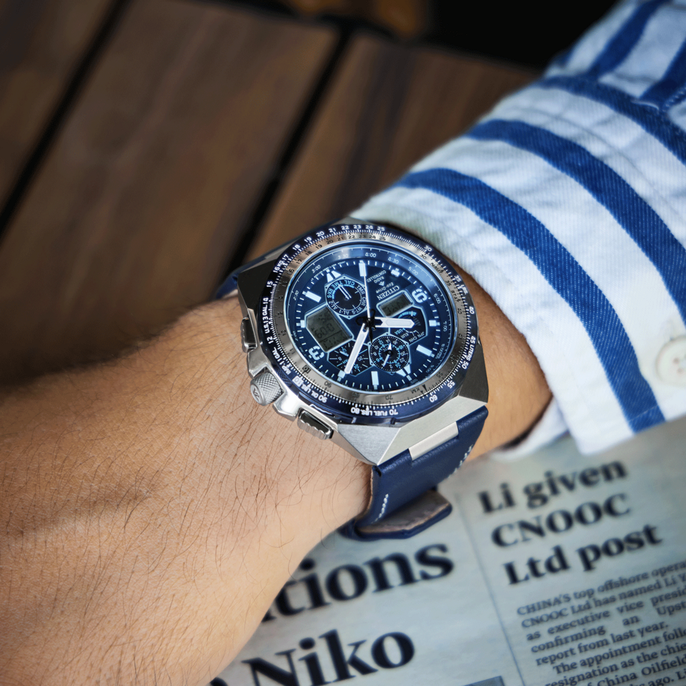 Montre-bracelet avec bracelet bleu au bras d'une personne, journal en arrière-plan.