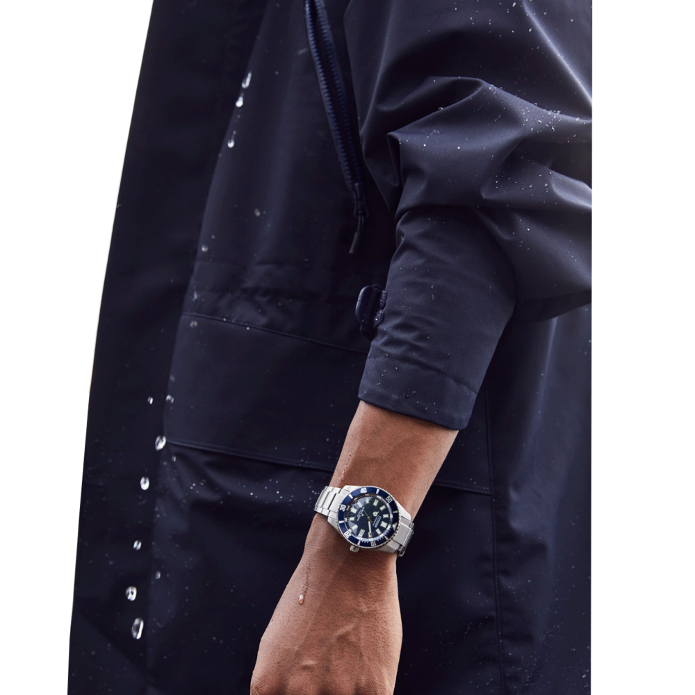 Homme portant une montre, veste bleu foncé, gouttelettes d'eau, gros plan, poignet