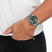 Homme portant une montre argentée avec un cadran vert, main dans la poche.