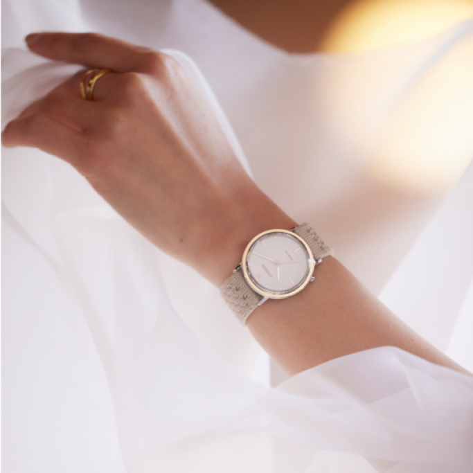 Gros plan d'une montre-bracelet avec un bracelet beige au poignet d'une femme.