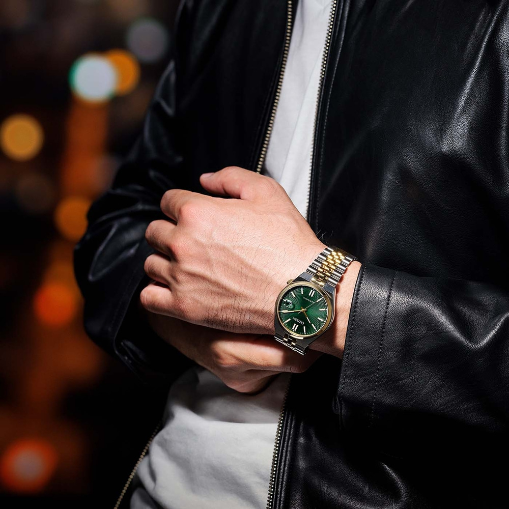 Homme portant une montre avec un cadran vert et un bracelet or et argent