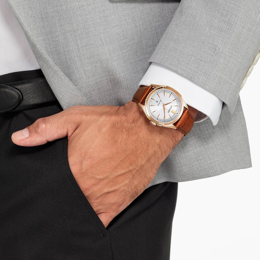 Homme portant une montre, un costume et la main dans sa poche.